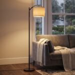 Arc floor lamp glowing warmly beside window on a rainy day