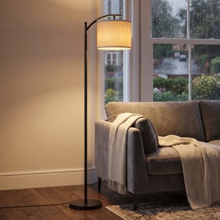 Arc floor lamp glowing warmly beside window on a rainy day